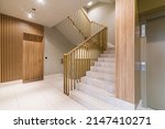 Staircase in modern block of flats. Finished with wood wall panels, tile floor. Interesting balustrade.