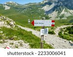 Small photo of Sovramonte, Italy - June 12, 2022: Hiking information post in Italian Alps Dolomiti mountains. Passo delle Vette Grandi with arrow pointing in path towards Monte Pavione. Background alpine peaks.