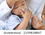 Small photo of Asian father rinsing baby's stuffy nose using a syringe of saline water - effective remedy for clearing a baby's clogged nose