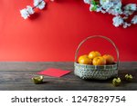 Small photo of Accessories on Lunar New Year & Chinese New Year vacation concept background.Orange in wood basket with red pocket money and flower on modern rustic brown & red backdrop at home office desk studio.