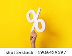 hand holding percentage sign over yellow background