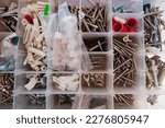 View of the transparent storage box, nuts, screws, screw boxes, small construction objects. Many storage compartments are full of accessories with screws, nuts, bolts neatly arranged.