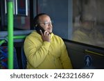 Small photo of a lustful dark-skinned young man is sitting in the bus and talking on the phone
