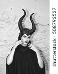 Small photo of Maleficent demonic - starring. Beautiful woman from a fairytale with hair horns outdoor. Beautiful girl with horns dressed up as devil. Woman with makeup, nail polish. Fantasy. Halloween concept.