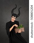 Small photo of Maleficent demonic - starring. Beautiful woman from a fairytale with hair horns indoor. Beautiful girl with horns dressed up as devil. Woman with makeup, nail polish. Fantasy. Halloween concept.