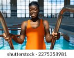 Small photo of Black young woman smiling while going downstairs into the water at the heated swimming pool
