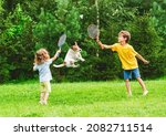 Small photo of Kids having fun playing badminton and dog jumping up to catch and steal shuttlecock