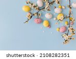 Happy Easter! Colorful Easter chocolate eggs with cherry blossoms flat lay on blue background. Stylish tender spring template with space for text. Greeting card or banner