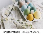 Happy Easter! Stylish Easter eggs and cherry blossoms on rustic linen cloth.  Natural dyed colorful pastel eggs in tray and spring flowers on rustic table. Countryside still life