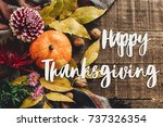 happy thanksgiving text sign on autumn pumpkin with leaves and walnuts and dahlias on stylish scarf top view, space for text. seasonal greetings, fall holidays. flat lay. harvest time. cozy mood