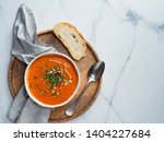 Gaspacho soup on round wooden tray over white marble tabletop. Bowl of traditional spanish cold soup puree gazpacho on light marble background. Copy space for text or design. Top view or flat lay.