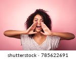 Young african woman shouting on pink background
