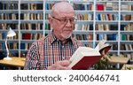 Small photo of Old Caucasian bald man in glasses and motley shirt reading book in library and studying. Close up of male professor with textbook researching in bibliotheca. Scientific work concept.