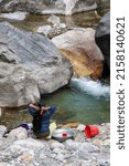 Small photo of A Sherpa girl preparing to wash her clothes in a small stream. Lukla, Nepal - 9 Mar 2012