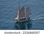 Small photo of To another adeventure, out to sea. A classic ship bore on but rough gray sails, slices through blue steely waters of California. The Junker style ship is on to new sights and errands far from home