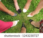 Small photo of Shoes in a circle. A group of formally dressed ladies in a circle with one shoed foot forward.