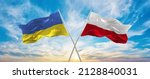 crossed national flags of Ukraine and poland flag waving in wind at cloudy sky. Symbolizing relationship, dialog, travelling between two countries. Copy space. 3d illustration