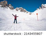 Small photo of St. Anton am Arlberg. March 10, 2022. Young snowboarder with arms outstretched standing on mountain slope at ski resort, Male snowboarder rising his hands up on snowy mountain