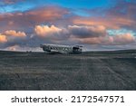 View of abandoned plane wreck at black sand beach. Broken airplane in Solheimasandur against cloudy sky. Scenic view of famous tourist attraction during sunset.