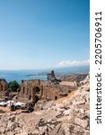 Rocks at old ruins of ancient Greek theater by Mediterranean sea. Building structure at Giardini Naxos bay with blue sky in background. View of historic famous tourist attraction on sunny day.