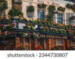 Small photo of London, UK. July 10, 2023. Closeup shot of Churchill Arms with flowering plants. Famous pub of London in city. Iconic landmark covered with flowers.