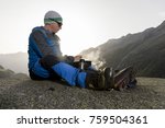 Alpinist pauses and prepares a warm drink, Switzerland