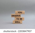 Small photo of You deserve to be well symbol. Wooden blocks with words You deserve to be well. Beautiful grey background. You deserve to be well concept. Copy space.