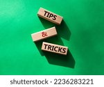 Small photo of Tips and tricks symbol. Wooden blocks with words Tips and tricks. Beautiful green background. Business concept and Tips and tricks. Copy space.