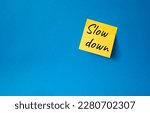 Small photo of Slow down symbol. Orange steaky note with words Slow down. Beautiful blue background. Business and Slow down concept. Copy space.