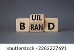 Small photo of Build your brand symbol. Turned wooden cubes with words Build and Brand. Beautiful grey background. Build your brand and business concept. Copy space