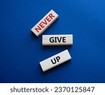 Small photo of Never give up symbol. Concept words Never give up on wooden blocks. Beautiful deep blue green background. Business and Never give up concept. Copy space.
