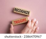 Small photo of Recognize triggers symbol. Concept words Recognize triggers on wooden blocks. Businessman hand. Beautiful pink background. Business and Recognize triggers concept. Copy space.