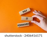 Small photo of Pay it forward symbol. Concept words Pay it forward on wooden blocks. Beautiful orange background. Businessman hand. Business and Pay it forward concept. Copy space.