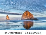 Dramatic coastal seascape featuring scenic rock formations in vivid sunrise colors. Location: Haystack Rock, Cannon Beach, Oregon, USA