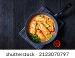 Small photo of Poached Salmon in Coconut Lime Sauce, salmon fish curry in a pan on a dark wooden table, view from above, flat lay, free space