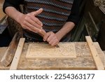 Small photo of Fez, Morocco - 24 May 2018: close-up of male woodcarver hands with a chisel carving a block of wood. Woodworker at a woodshop in Fes el Bali. Woodcarving in progress. Fes horizontal travel background.
