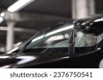Small photo of Car windshield wiper cleaning water drops from glass. Car wash concept. Close up of modern style of car windshield wiper