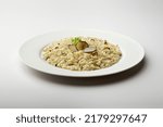 White dinner plate with risotto and slices of black truffle isolated on white background