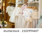 Small photo of Display rack with first communion dresses for girls in a luxury children's clothing shop.