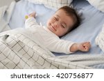 Smiling baby girl lying on a bed sleeping on blue sheets
