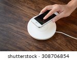 a hand putting mobile phone on a wireless charger, modern equipment, hard wood floor