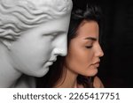 Profile portrait of a young beautiful woman standing next to a gypsum sculpture of Venus