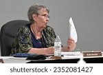 Small photo of MARION, KANSAS, USA - AUGUST 21, 2023 Marion City Vice Mayor Ruth Herbel holds up a sheet of paper if anybody wants to sign up to speak at the next city council meeting