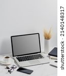 Small photo of modern lap top template mock up on white and clean work desk with blank screen Workspace desk, laptop, coffee cup and pen laptop mock up screen view. work from home concept