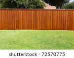 A pleasant sunny backyard with green grass and a nice wood fence.