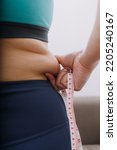 Small photo of Beautiful fat woman with tape measure She uses her hand to squeeze the excess fat that is isolated on a white background. She wants to lose weight, the concept of surgery and break down fat under the
