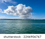Small photo of Yachts sailing on the green colored sea with a huge cumulonimbus cloud. Beyond the sea, towns and mountains are clearly seen.