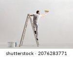Rear view of a painter painting a wall on a ladder isolated on white background