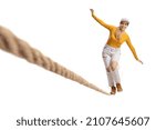 Small photo of Full length portrait of a young female trying to walk on a tightrope isolated on white background
