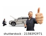 Small photo of Mechanic in a uniform holding a wrench and gesturing thumbs up and other worker checking a SUV in the back isolated on white background
